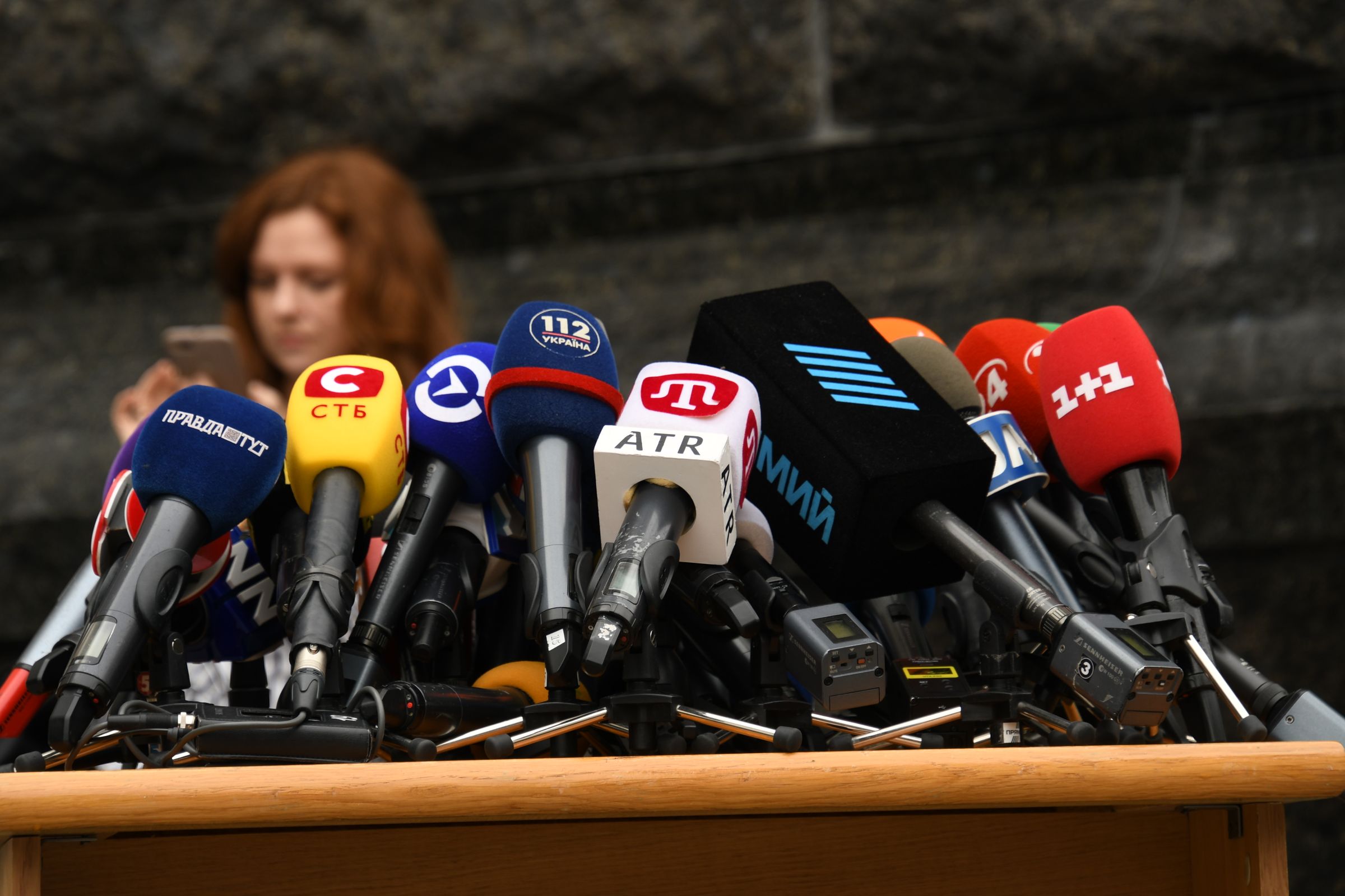 A wall of press microphones at a podium, the free press carrying Ida B. Wells' fight for truth forward