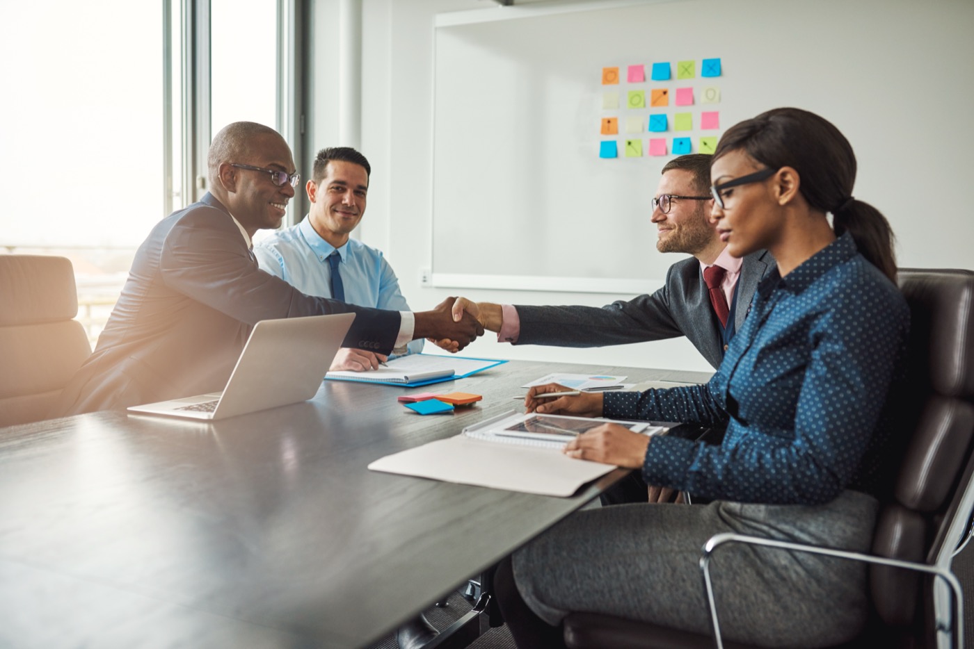 Two diverse teams reaching an agreement with a handshake