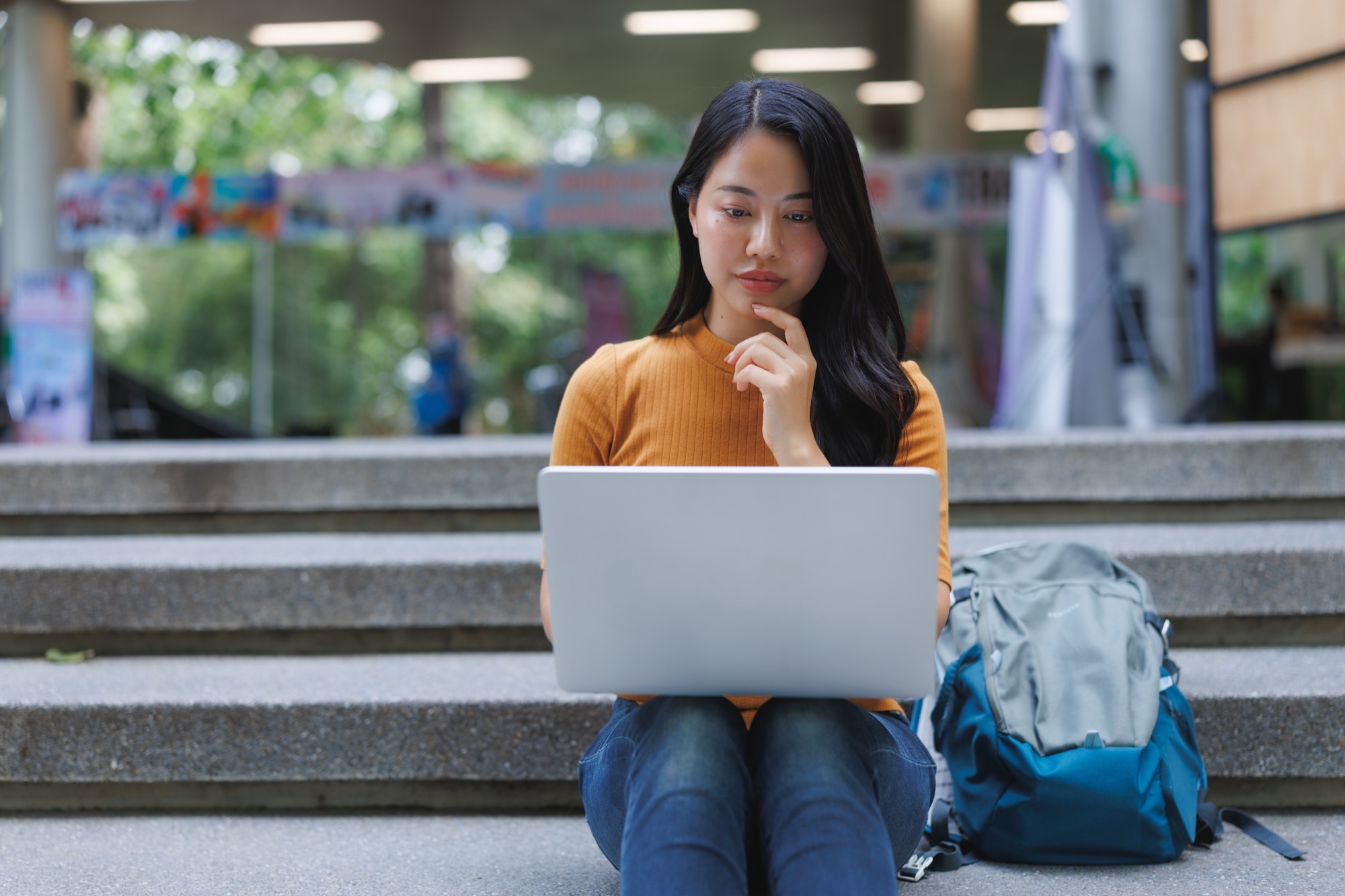 A young professional working on a laptop outdoors, carrying Ida B. Wells' pen forward